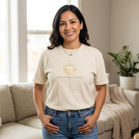 Latina woman wearing Sagittarius Mama ivory zodiac graphic t-shirt standing indoors with hands in pockets