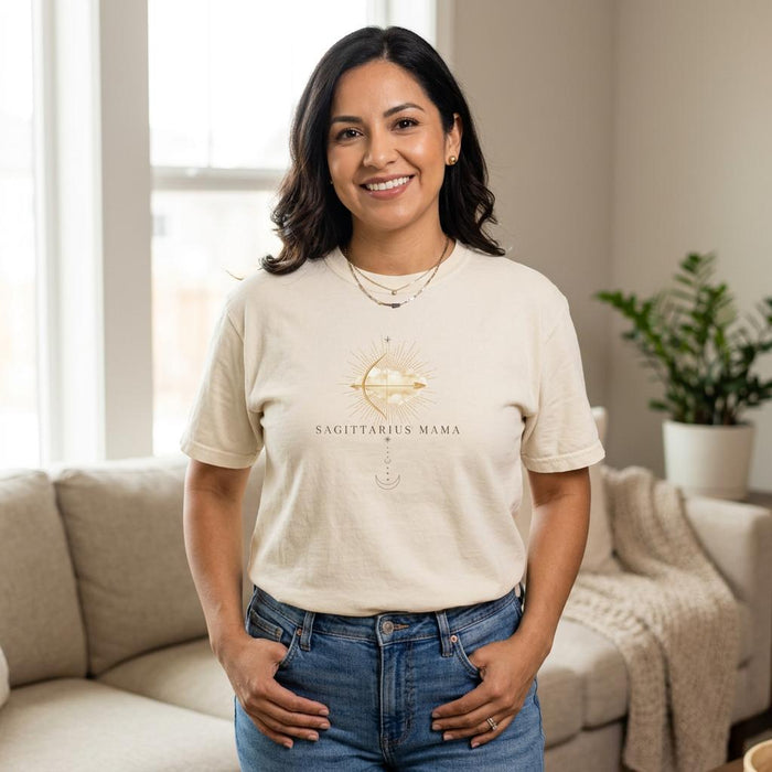 Latina woman wearing Sagittarius Mama ivory zodiac graphic t-shirt standing indoors with hands in pockets