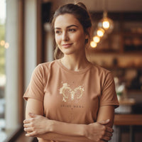 Load image into Gallery viewer, Close-up of woman modeling sandstone Aries Mama zodiac t-shirt showing watercolor ram chest design
