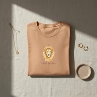 Load image into Gallery viewer, Folded sandstone Leo Mama zodiac t-shirt with celestial lion artwork styled in a neutral flat lay with jewelry and ceramic decor