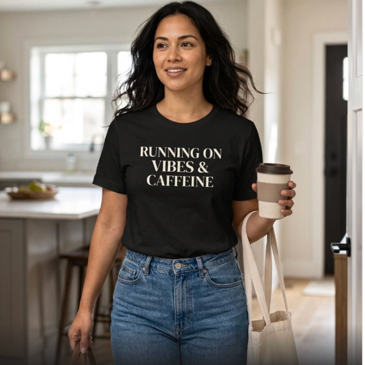Woman wearing black “Running on Vibes & Caffeine” t-shirt indoors holding coffee, relaxed mom lifestyle outfit