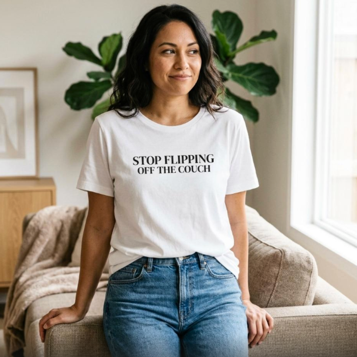 Woman wearing white “Stop Flipping Off the Couch” graphic t-shirt sitting by window, relaxed casual mom outfit
