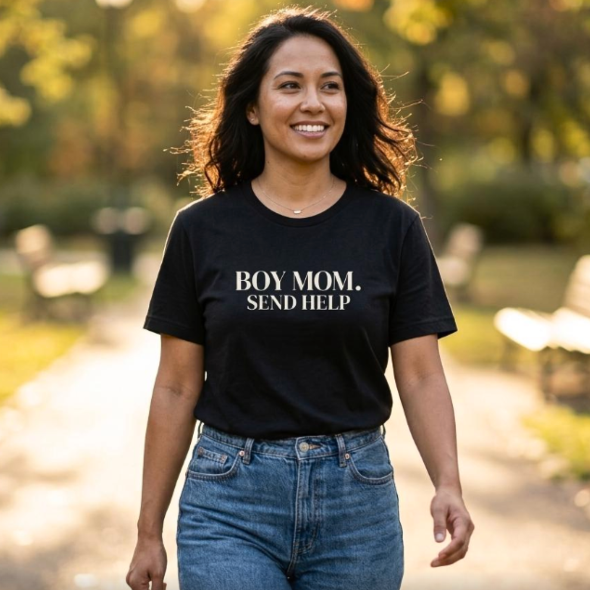 Woman wearing black “Boy Mom. Send Help” t-shirt walking outdoors, casual everyday mom outfit with jeans