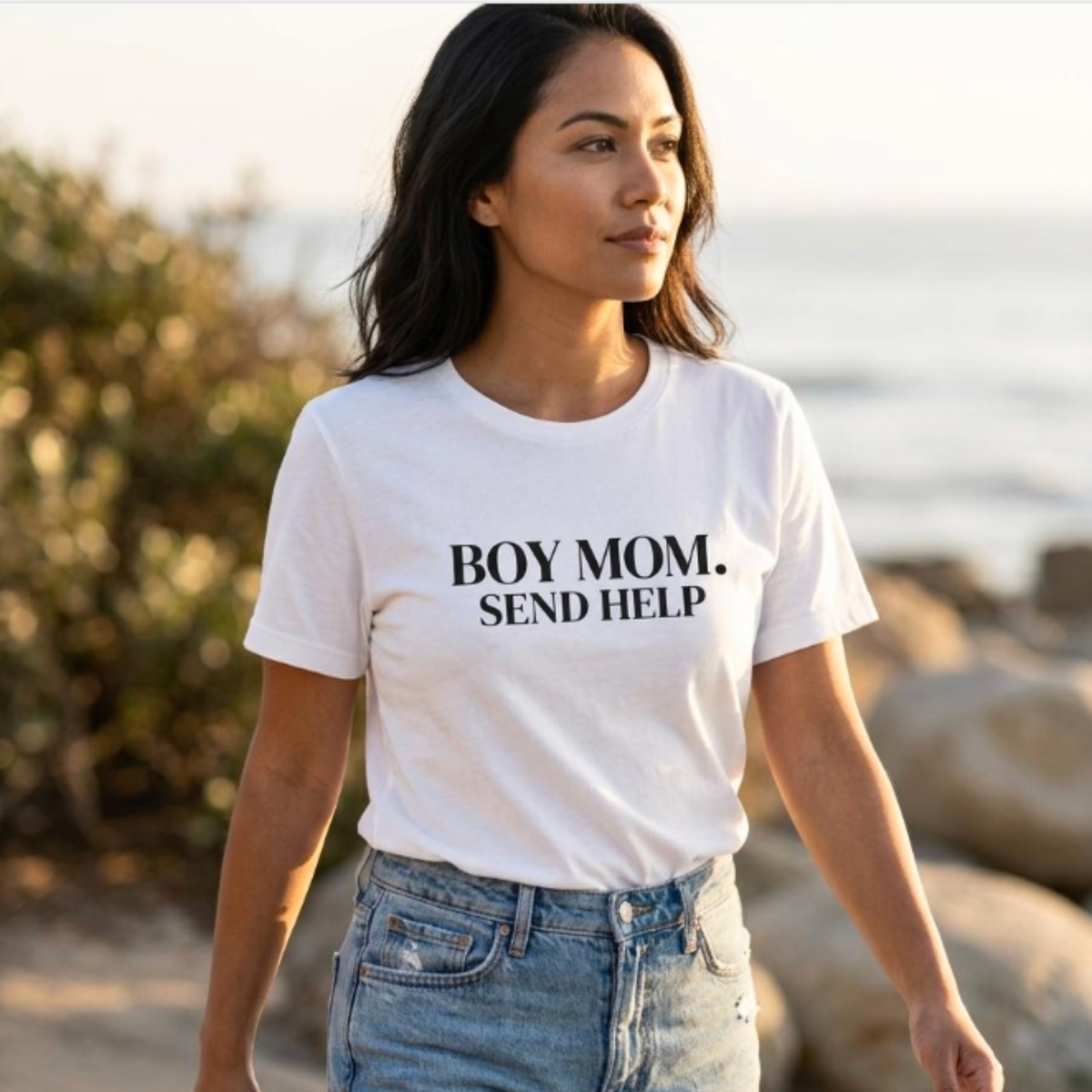 Woman wearing white “Boy Mom. Send Help” t-shirt walking outdoors, casual mom outfit with jeans
