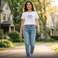Woman wearing white “Chaos, But Make It Cute” graphic tee walking outdoors, casual everyday style