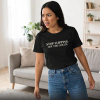 Woman wearing black “Stop Flipping Off the Couch” graphic t-shirt reacting playfully in living room, casual mom outfit