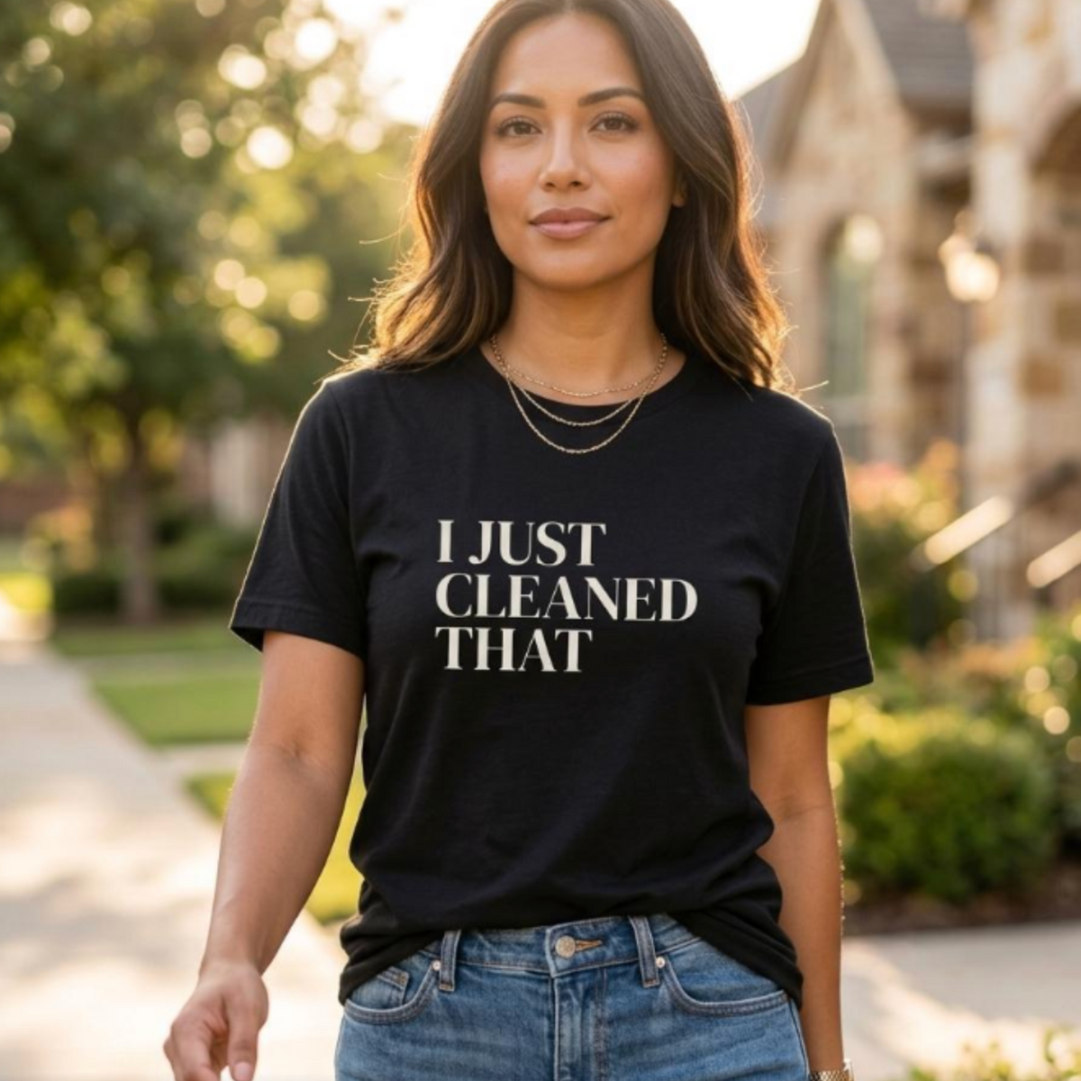 Woman wearing black “I Just Cleaned That” graphic t-shirt walking outdoors, casual everyday mom outfit