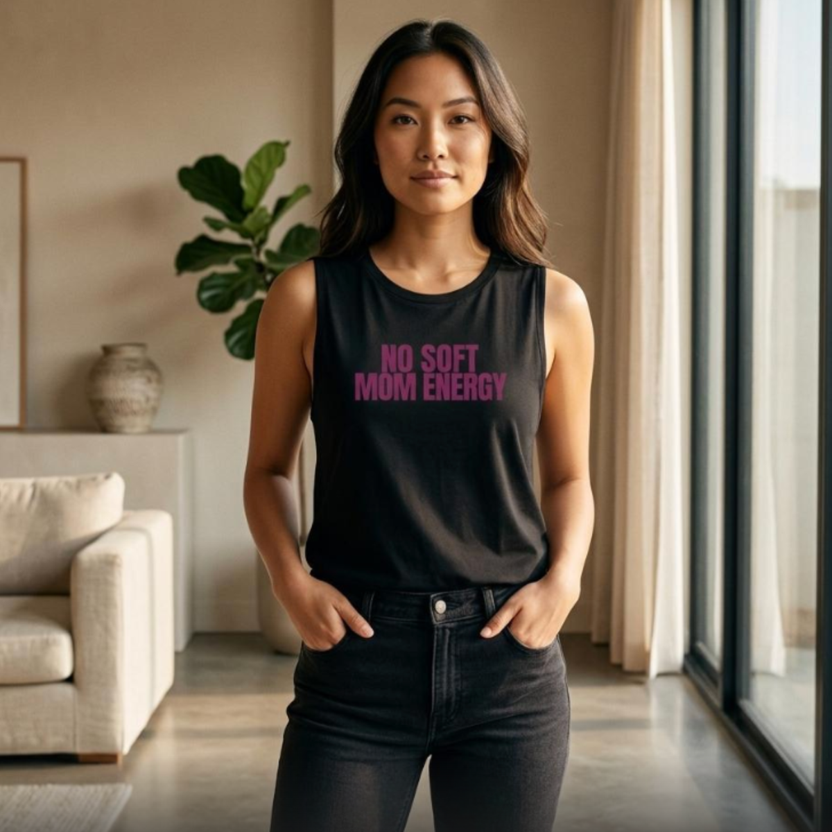 Woman standing indoors wearing black “No Soft Mom Energy” muscle tank and black jeans