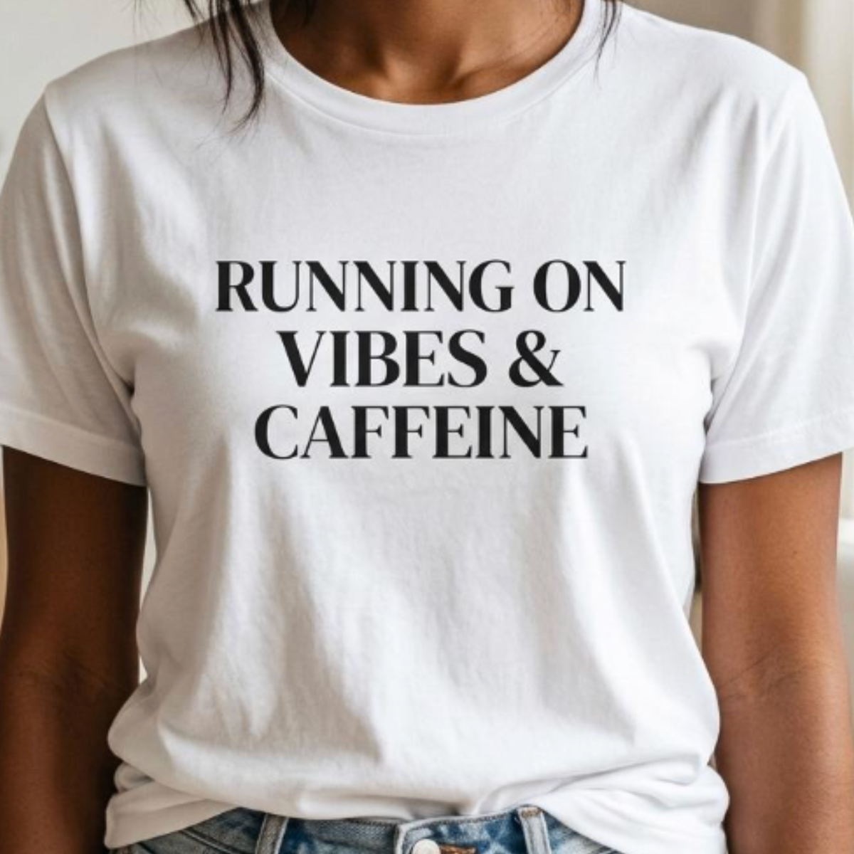 Close-up of white “Running on Vibes & Caffeine” graphic t-shirt showing bold black typography