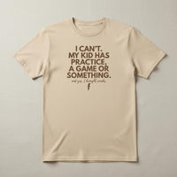 Load image into Gallery viewer, Flat lay of cream unisex mom t-shirt with “I can’t. My kid has practice, a game or something” text