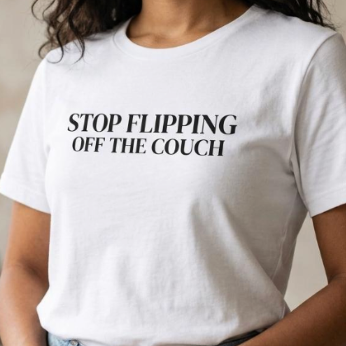 Close-up of white “Stop Flipping Off the Couch” graphic t-shirt with bold black typography