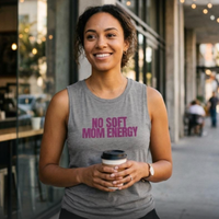 Woman holding coffee wearing gray “No Soft Mom Energy” muscle tank on city street