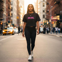 Woman walking in the city wearing a black cropped Champion Raise Heavy Raise Legends t-shirt