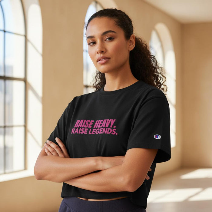 Woman modeling a black cropped Champion t-shirt with pink Raise Heavy Raise Legends graphic in studio portrait