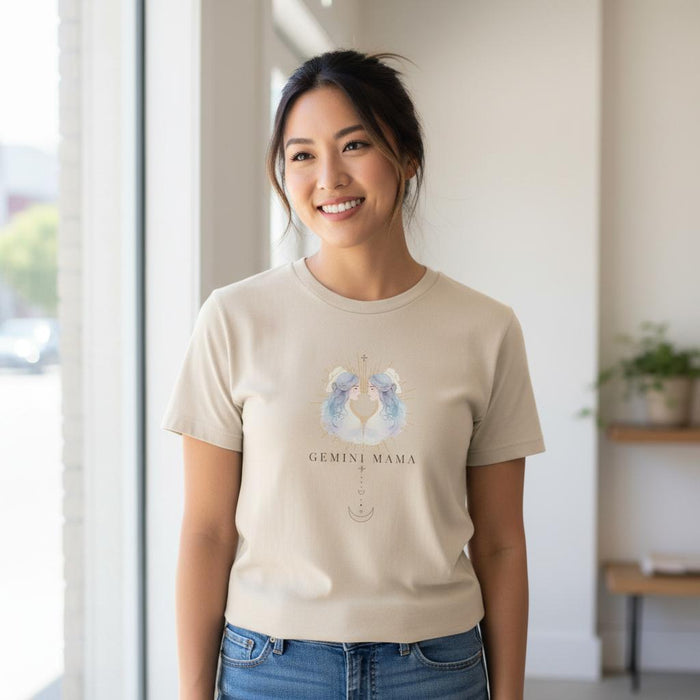 Woman wearing ivory Gemini Mama zodiac t-shirt indoors near window, watercolor twin design visible