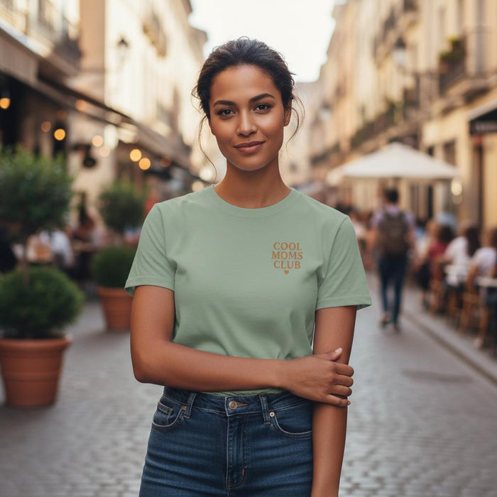 Woman wearing a green t-shirt with 'Cool Moms Club' text on a street.