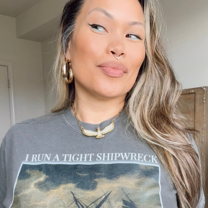 Woman wearing a gray t-shirt with a graphic design and text indoors.