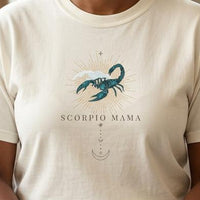 Close-up of Scorpio Mama ivory t-shirt with teal scorpion zodiac graphic on chest