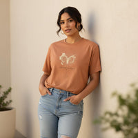 Load image into Gallery viewer, Woman wearing sandstone Aries Mama zodiac t-shirt with watercolor ram design against neutral wall