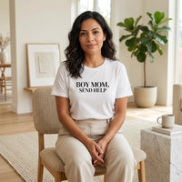White “Boy Mom. Send Help” graphic t-shirt on woman sitting indoors, neutral aesthetic casual mom outfit