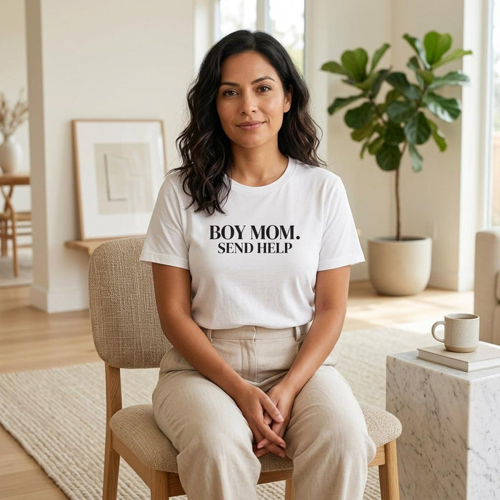 White “Boy Mom. Send Help” graphic t-shirt on woman sitting indoors, neutral aesthetic casual mom outfit