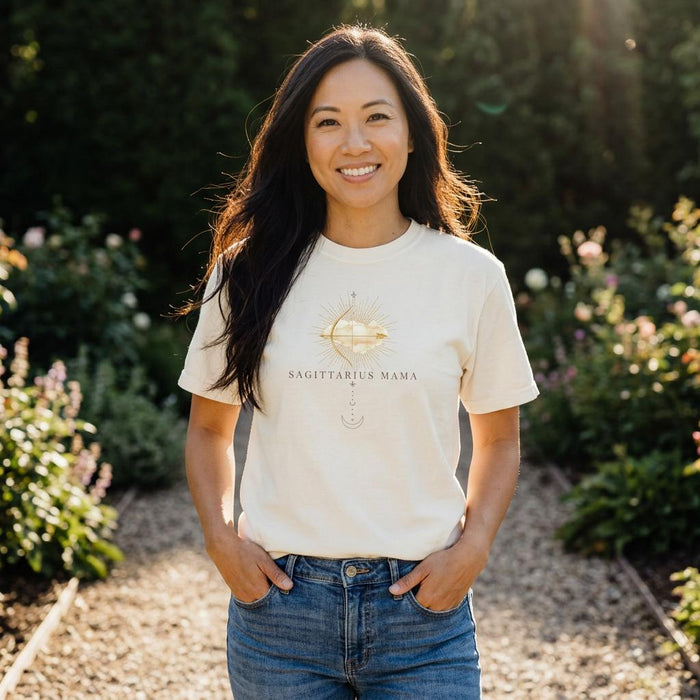 Asian woman wearing Sagittarius Mama ivory zodiac mom t-shirt outdoors with greenery background