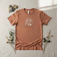 Load image into Gallery viewer, Flat lay of Taurus Mama sandstone zodiac graphic t-shirt styled on neutral linen with earthy accessories
