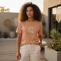 Load image into Gallery viewer, Woman wearing Taurus Mama sandstone zodiac graphic t-shirt outdoors in warm golden sunlight on a modern patio