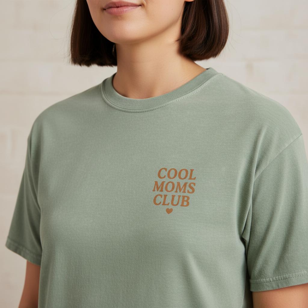 Woman wearing a green t-shirt with 'Cool Moms Club' text on a neutral background