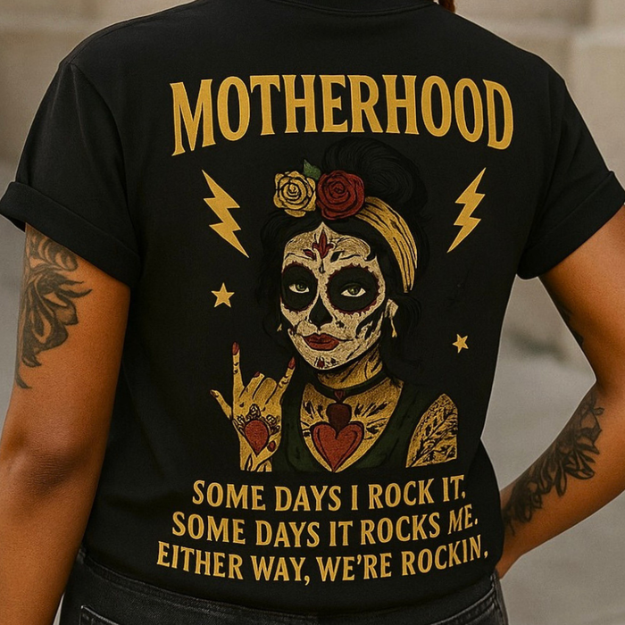 Close-up of a black t-shirt with a graphic design and text on the back, featuring a stylized face and tattoos.